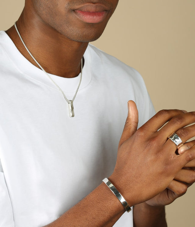 a mans hand wearing a liquid necklace and a wide liquid ring and a viper bangle